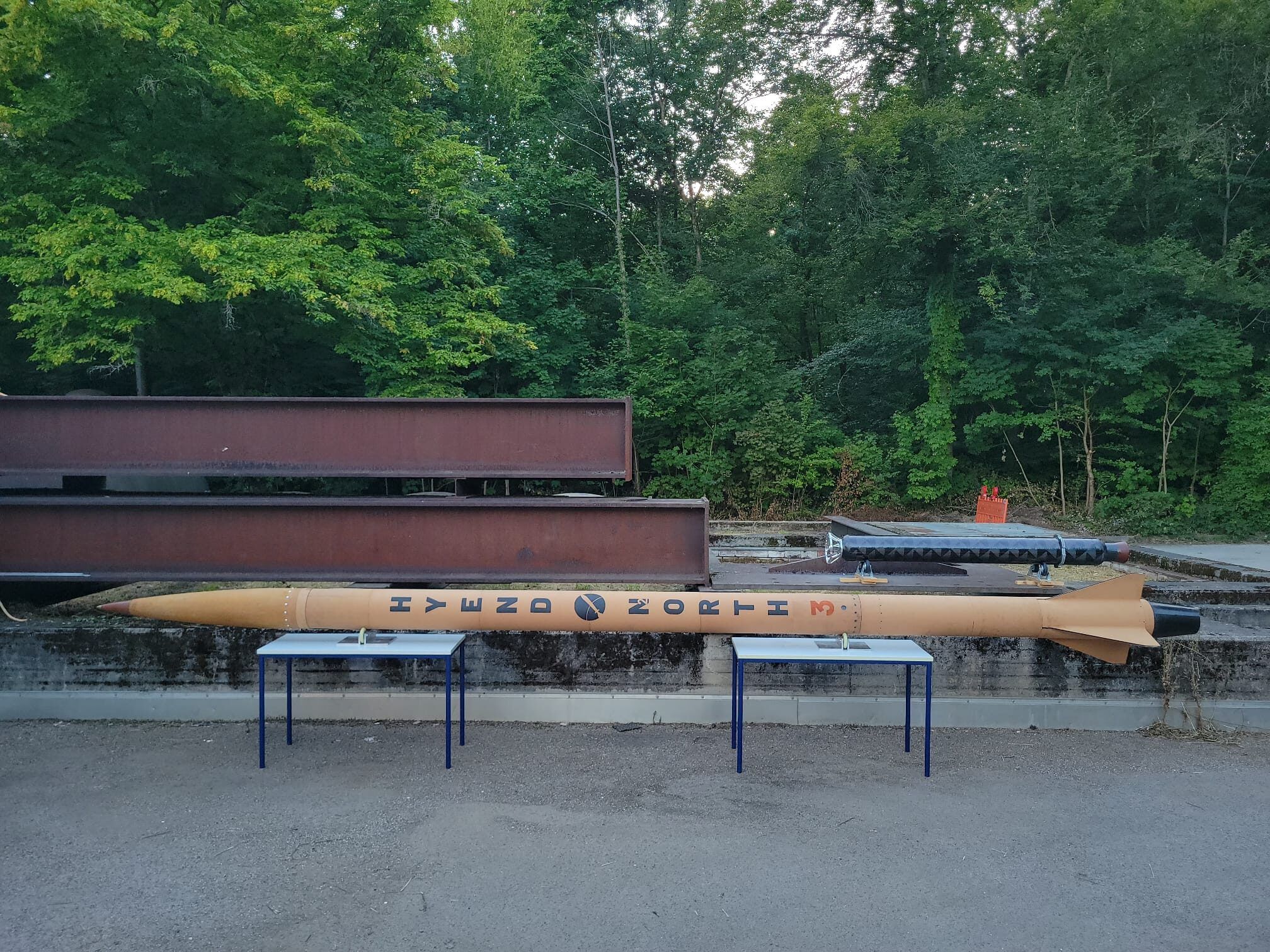 The N₂ORTH hybrid rocket resting horizontally on stands outdoors, showing its HyEnD N₂ORTH livery